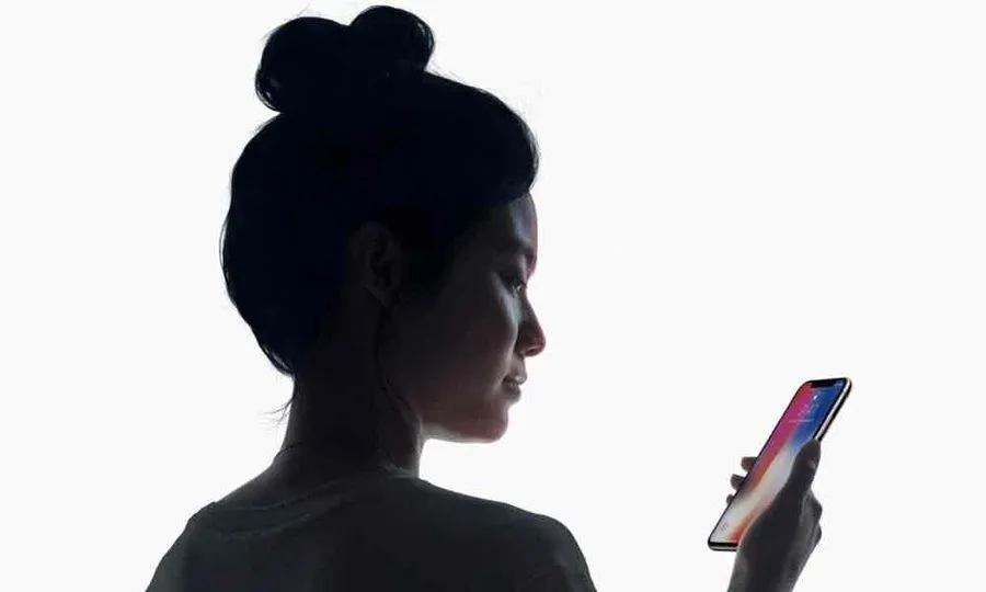 A screenshot of Apple's demonstration of FaceID phone unlocking. A woman is looking down at her iPhone